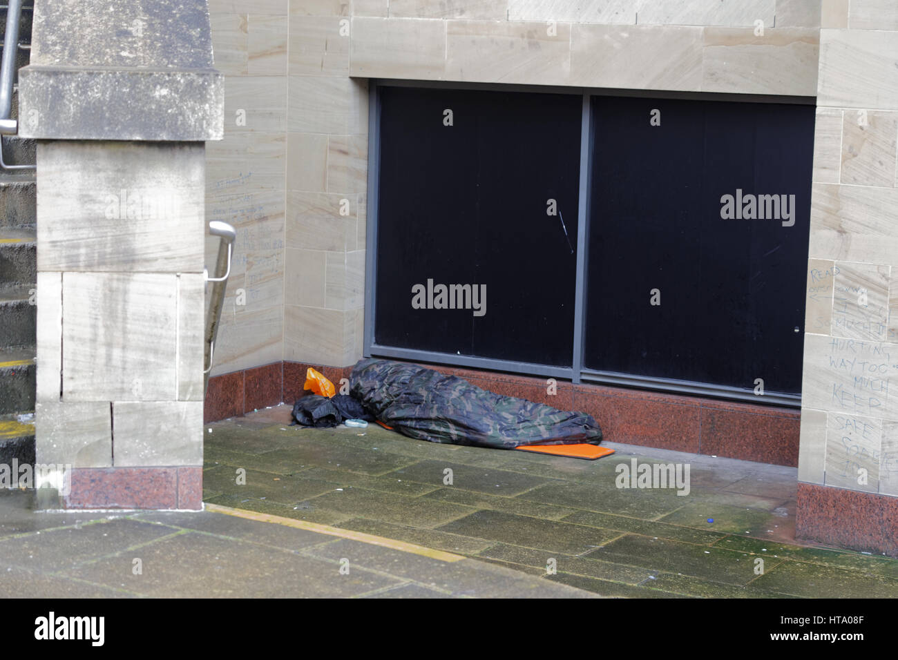 homeless in the uk begging on the street cameo camouflage sleeping bag Stock Photo