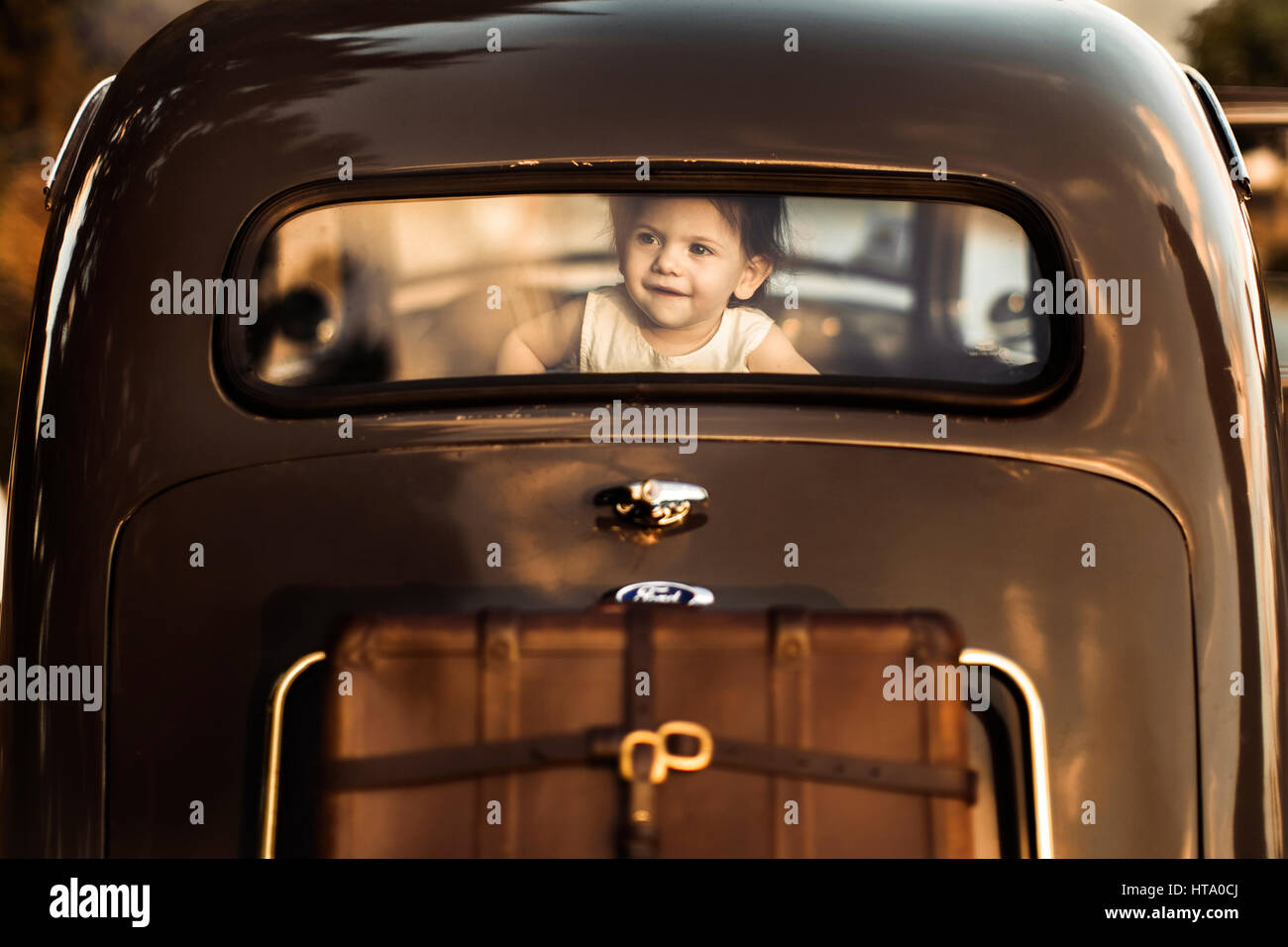 A little girl on a back seat of a retro car Stock Photo
