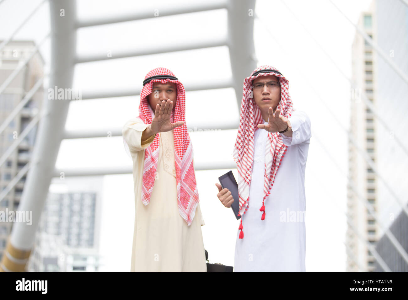 Two Arabian man making a halt gesture with he raised hand indicating a stop (selective focused) Stock Photo