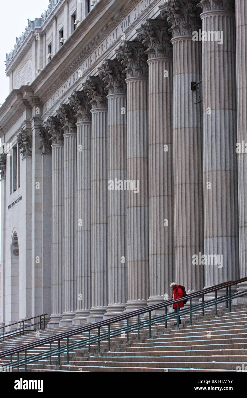 A lone figure outside the New York Post Office building on a snowy day. Stock Photo
