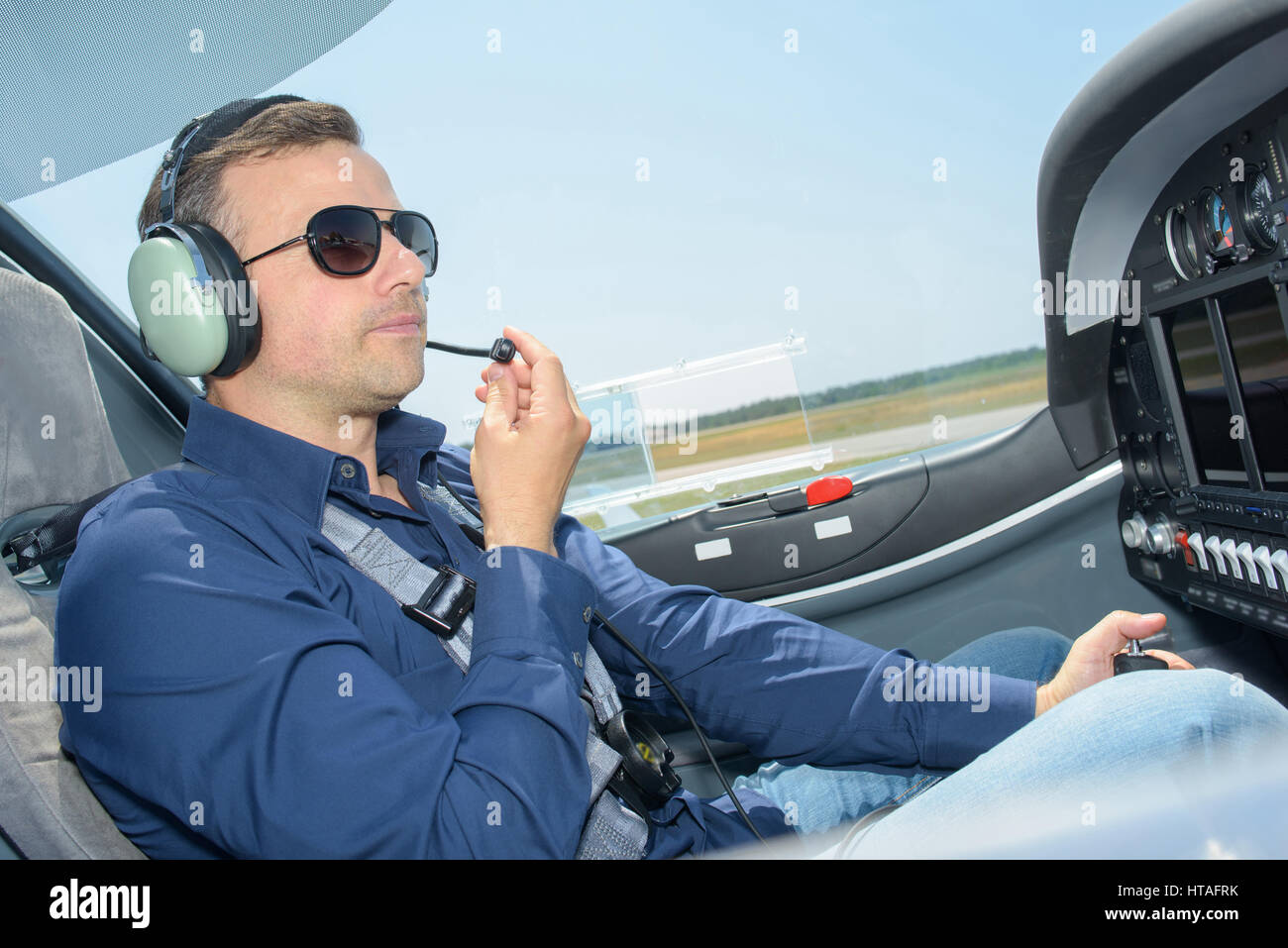 Man in cockpit of aircraft wearing headphones with microphone Stock