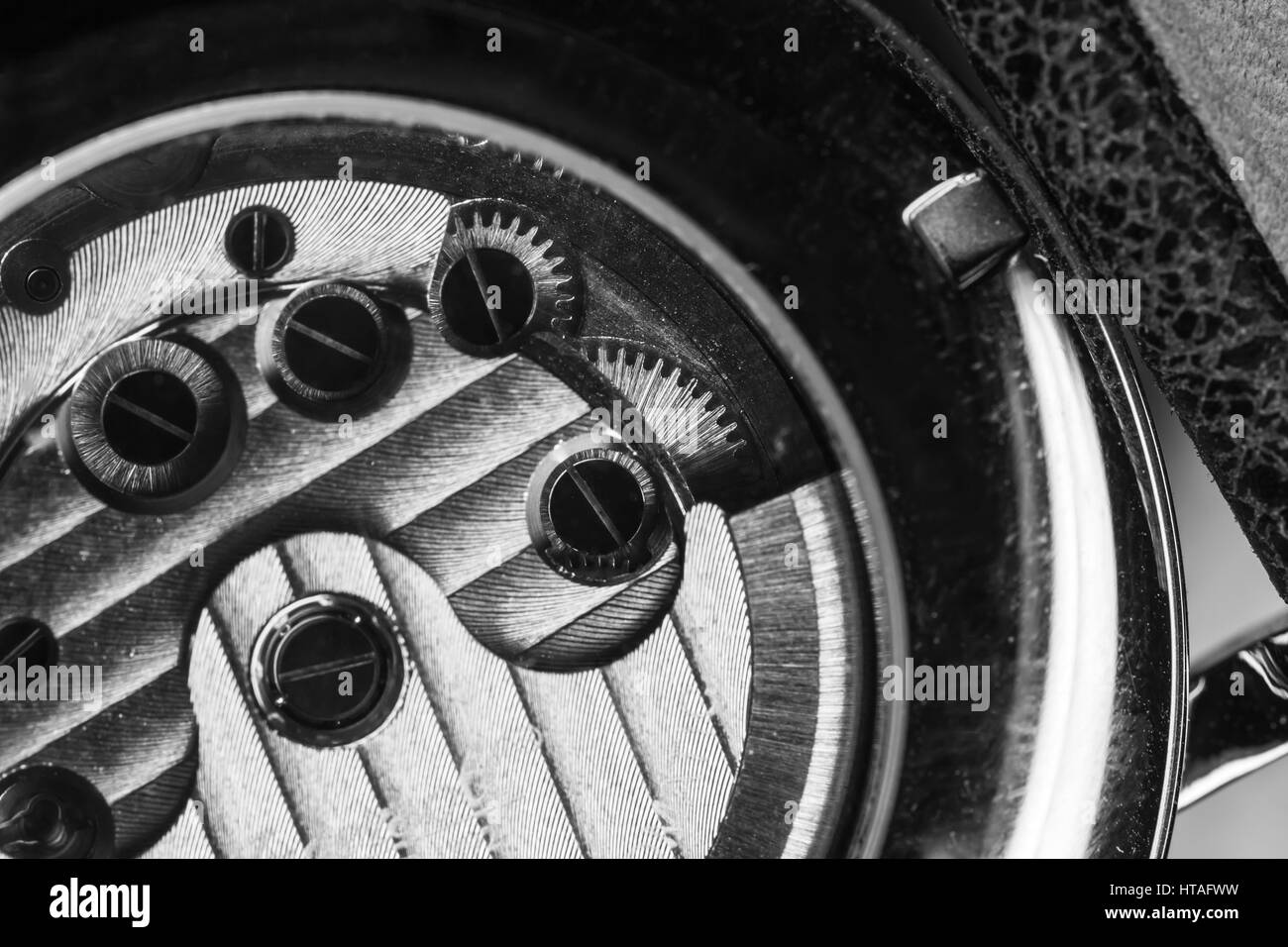 Mechanical men wrist watch with automatic winding, close-up fragment of open back side with self-winding mechanism details, black and white Stock Photo