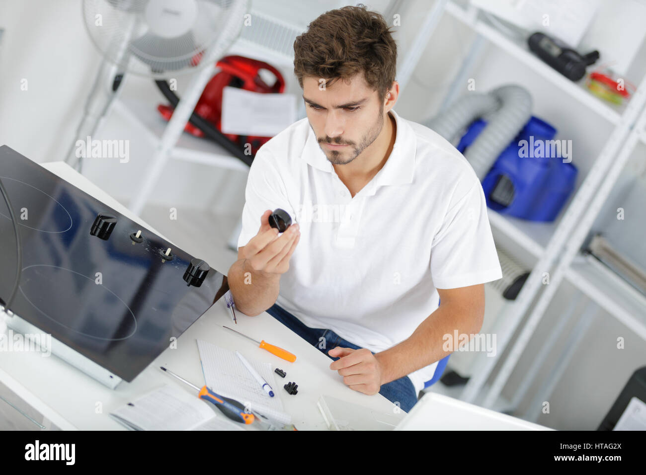 young repairman installing induction cooker in kitchen Stock Photo