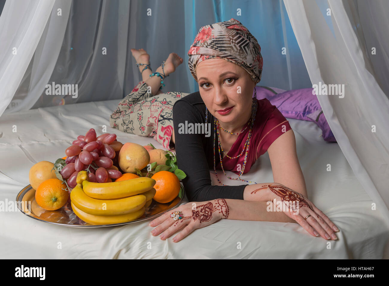 Oriental woman on bed in bedroom. Stock Photo