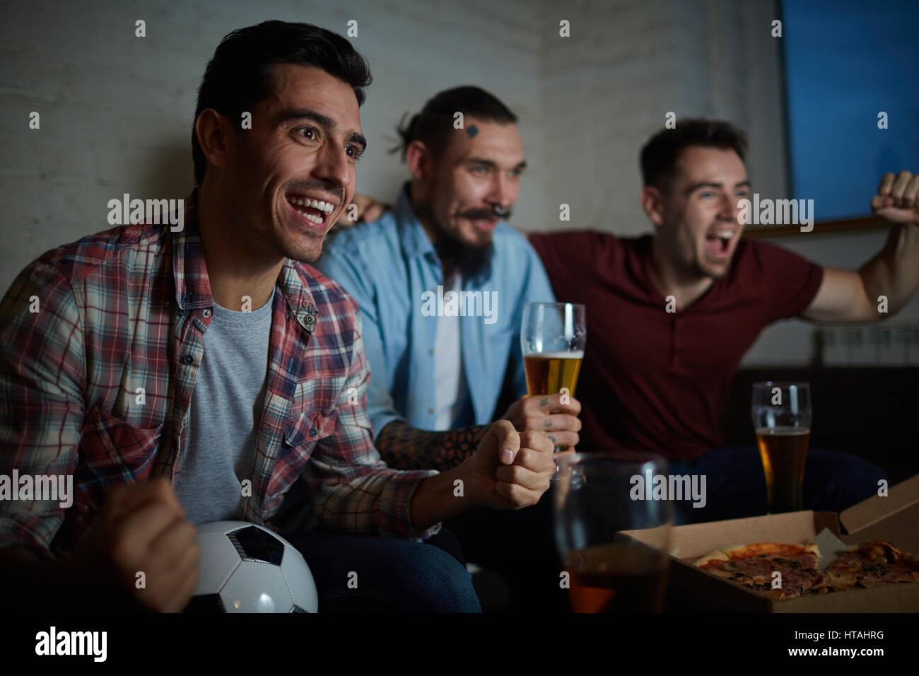 Ecstatic guys expressing gladness after football match Stock Photo