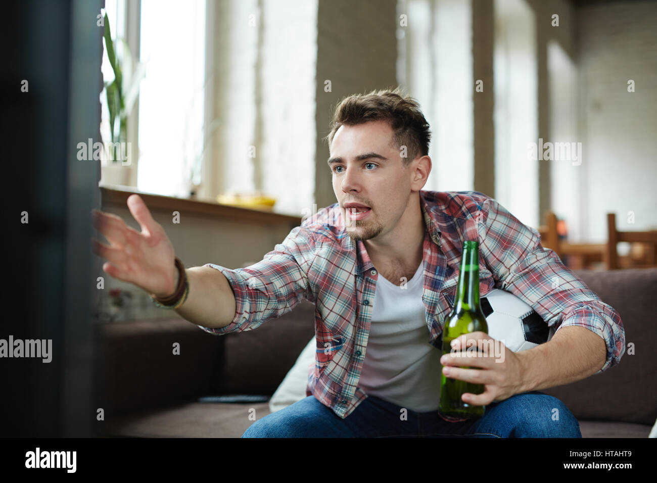 Football fan being nervous while watching broadcast of football game Stock Photo