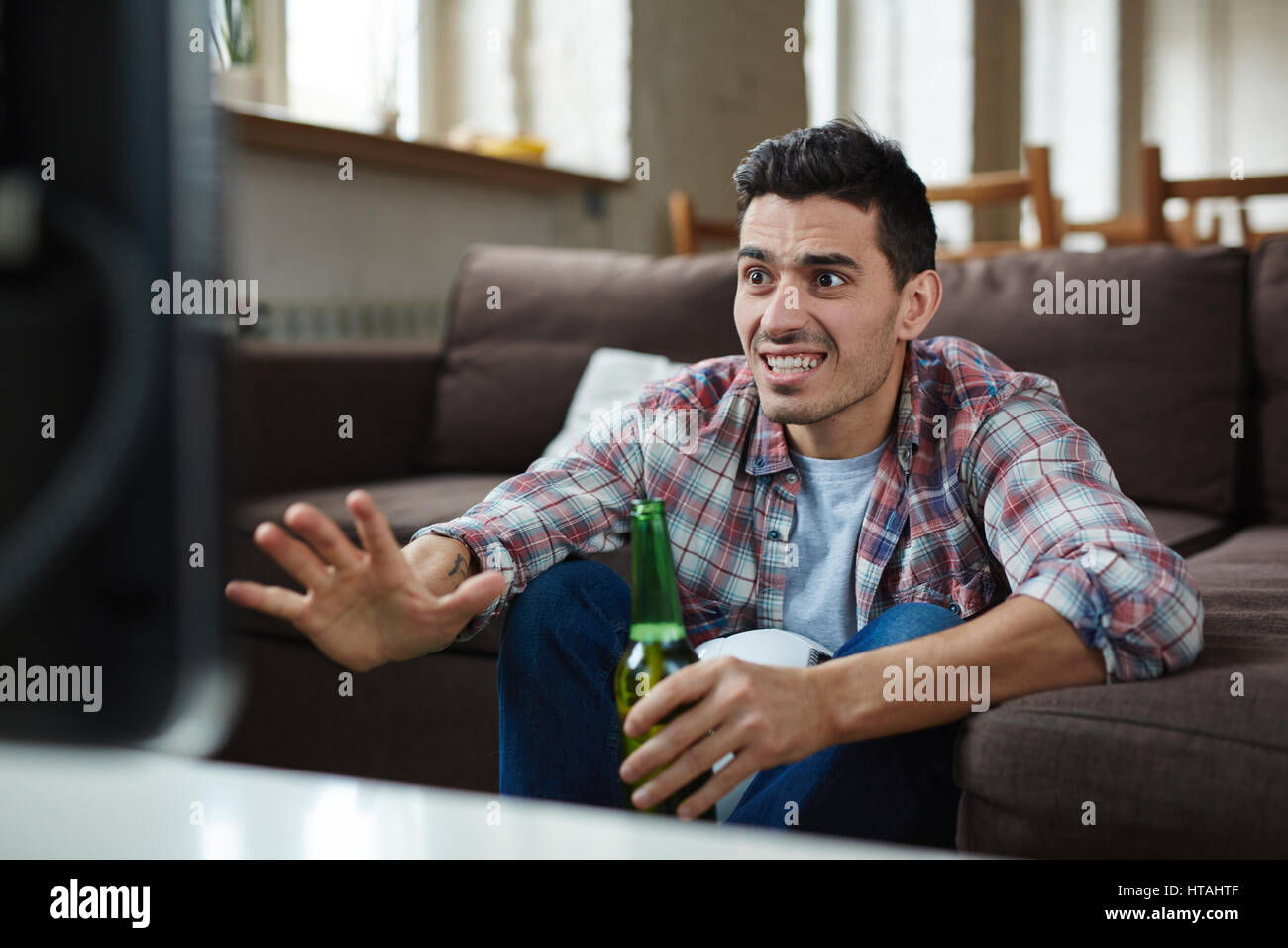 Guy with anxious expression sitting in front of tv set during football match Stock Photo