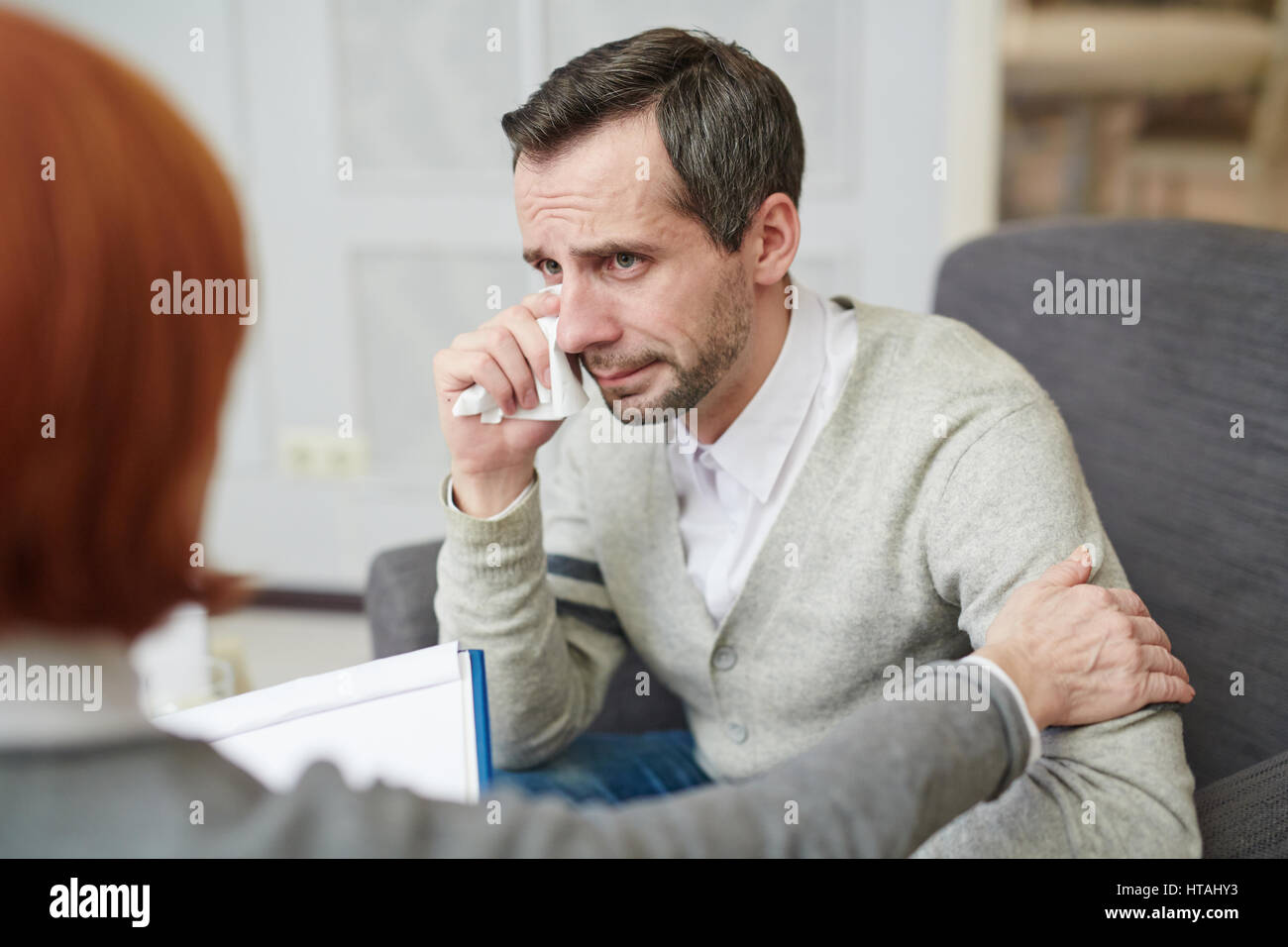 Crying man addicted to alcohol listening to his counselor Stock Photo