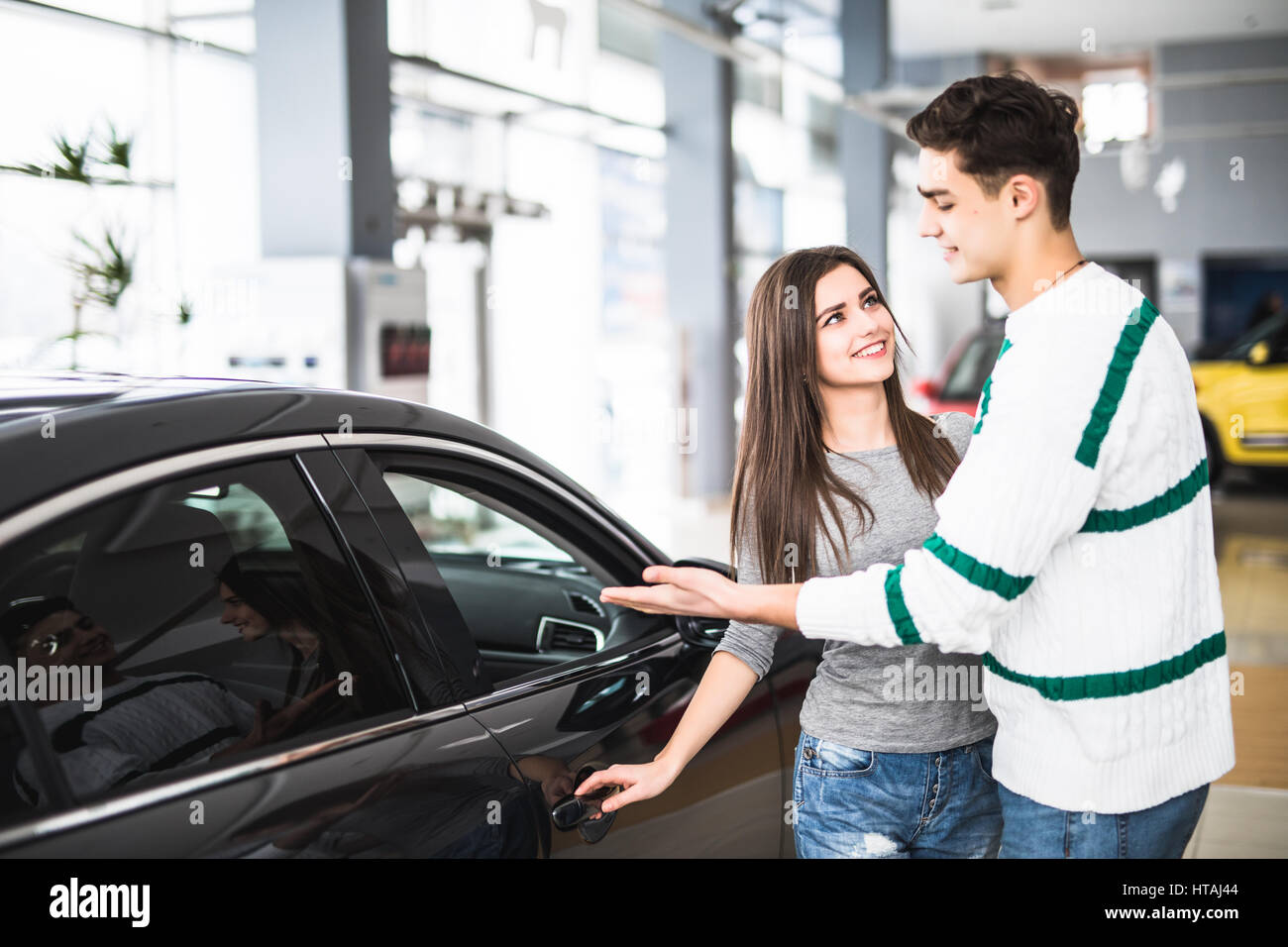 Young couple standing at the dealership choosing the car to buy Stock Photo