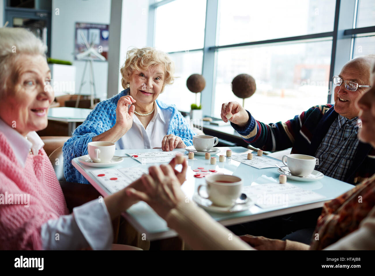 Happy senior man and women playing lotto and having tea Stock Photo