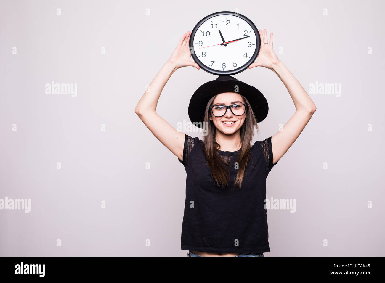 girl with the clock over head on grey background Stock Photo - Alamy
