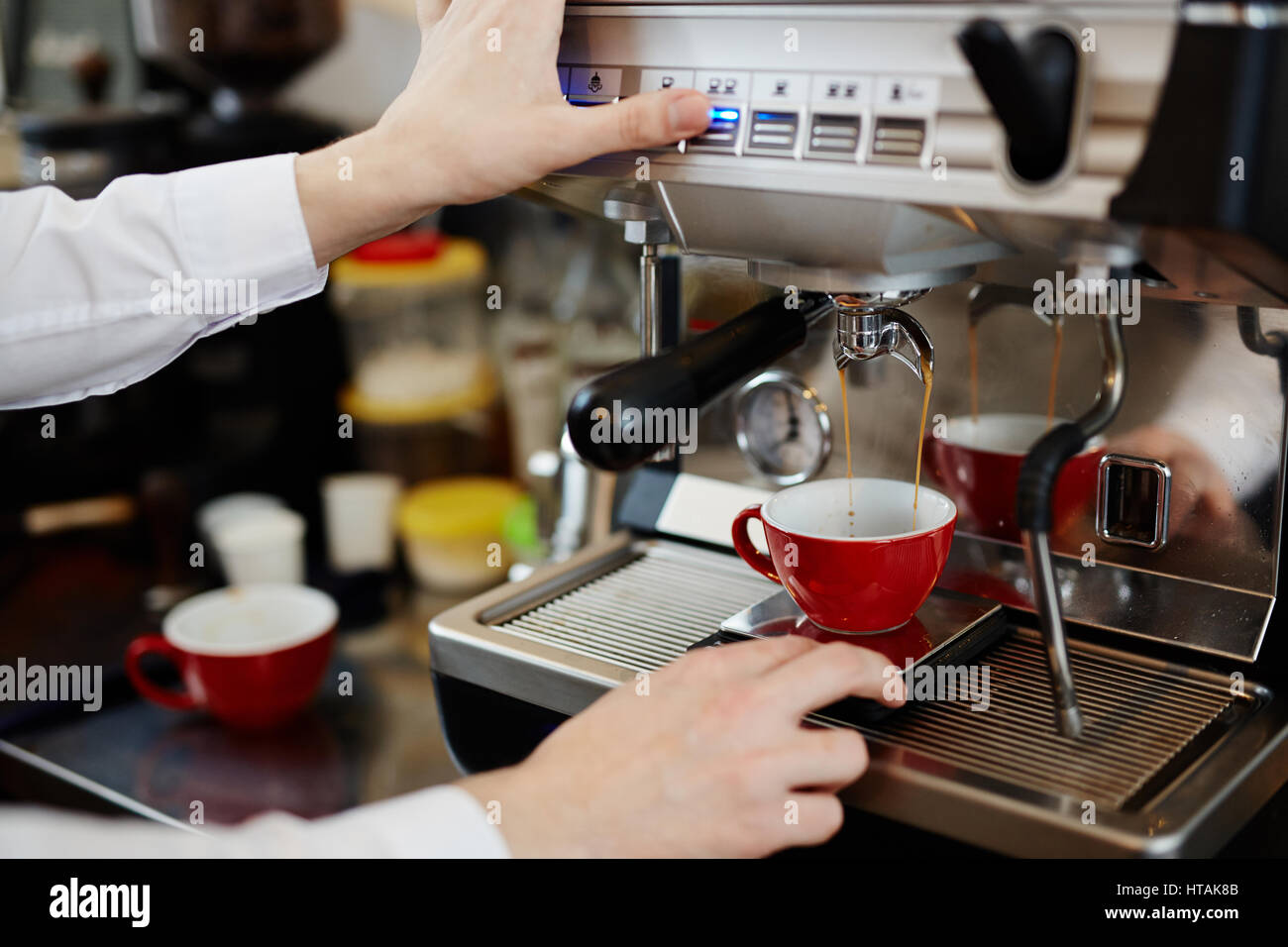Barista keeping his hands on coffeemachine control panel while fresh