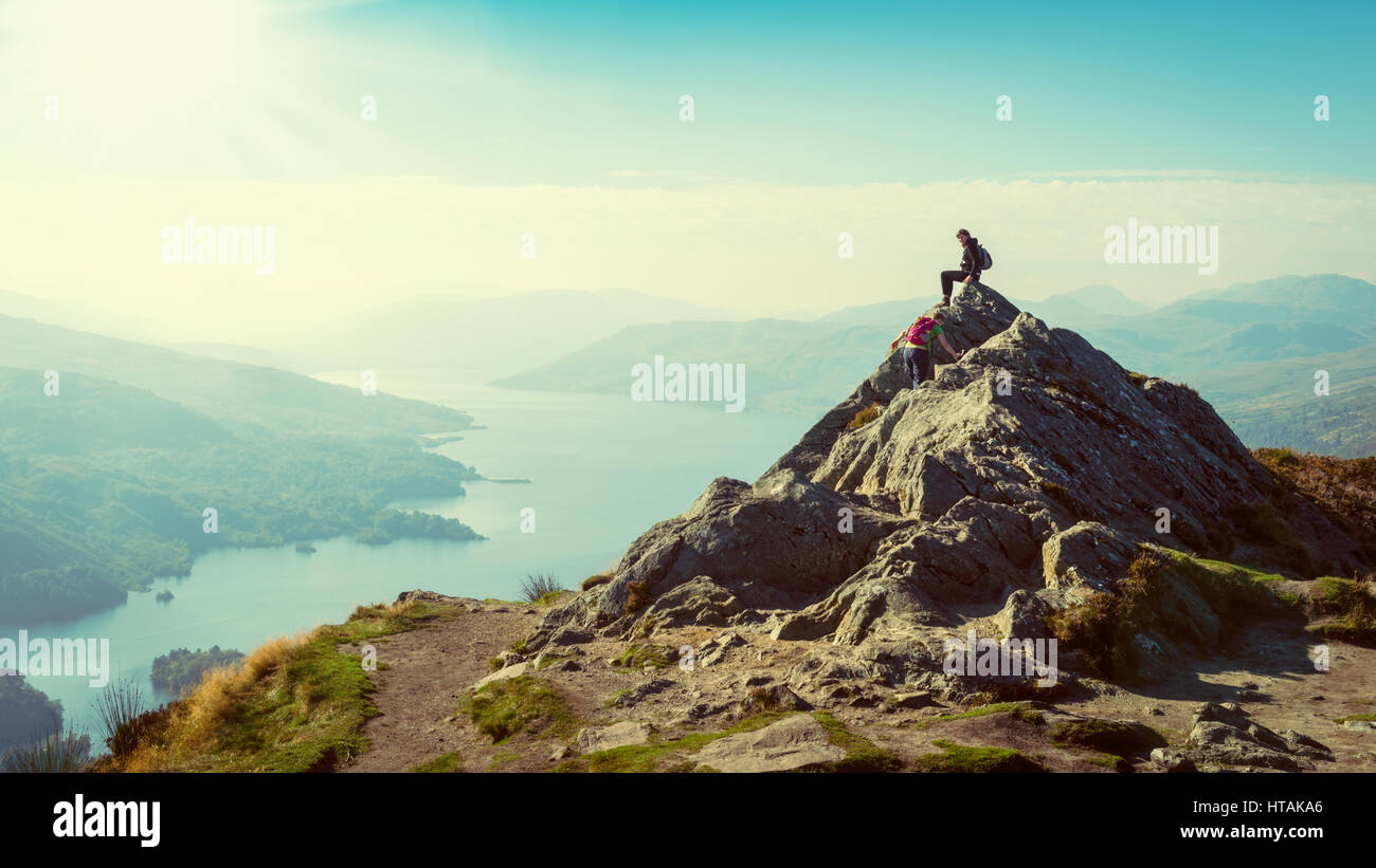 Two female hikers on top of the mountain enjoying valley view, Ben A'an, Loch Katrine, Highlands, Scotland, UK Stock Photo