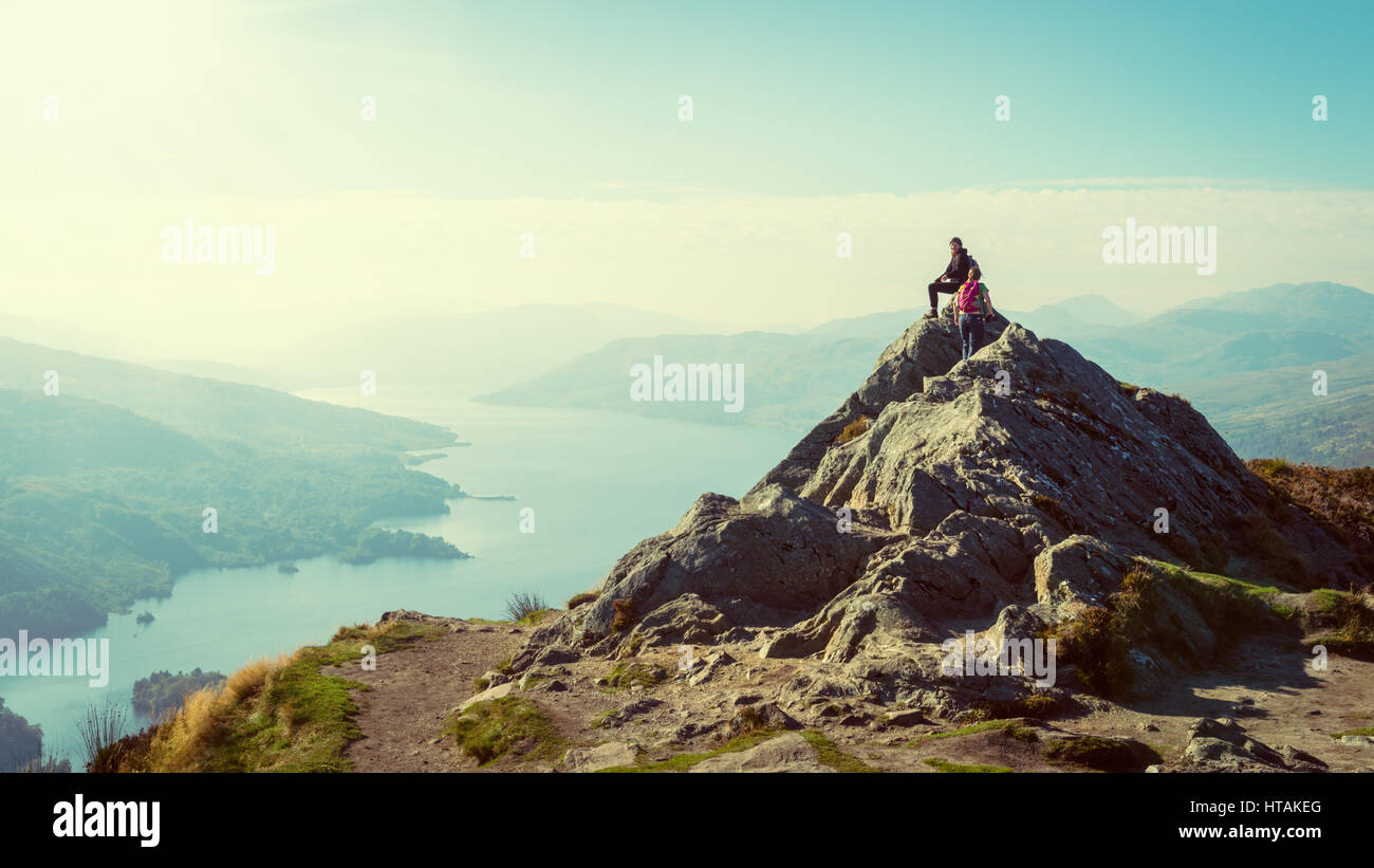 Two female hikers on top of the mountain enjoying valley view, Ben A'an, Loch Katrine, Highlands, Scotland, UK Stock Photo