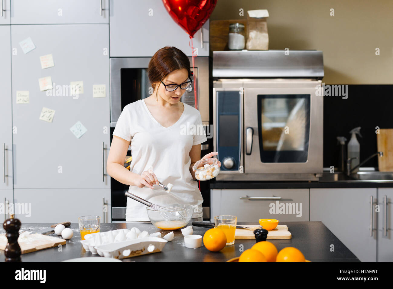 Housewife adding sugar into whisked eggs Stock Photo