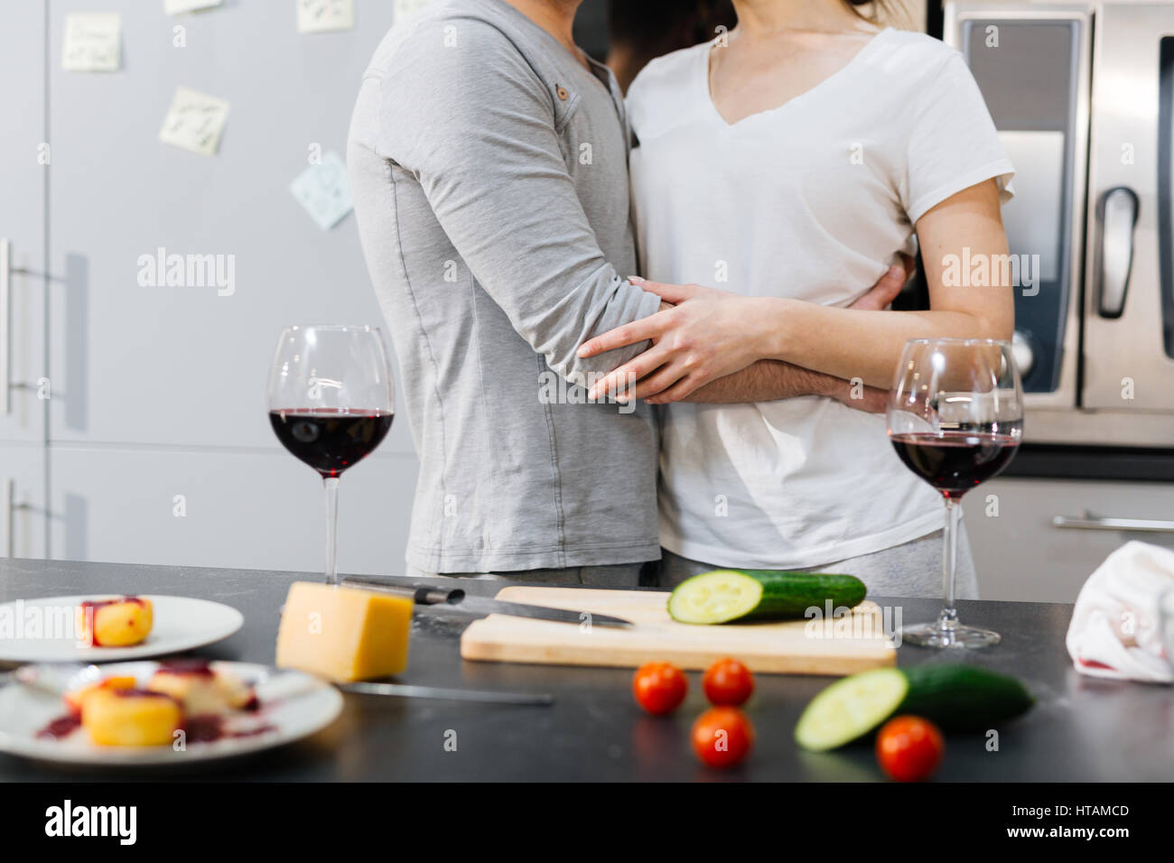 Bonding couple in embrace standing by kitchen table Stock Photo