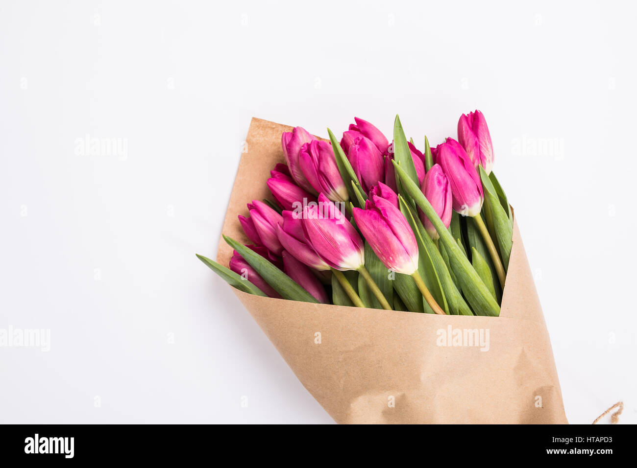 Pink tulips in a package of craft on the wooden background. Pink tulip. Tulips. Flowers. Flower background. Flowers photo concept. Holidays photo conc Stock Photo
