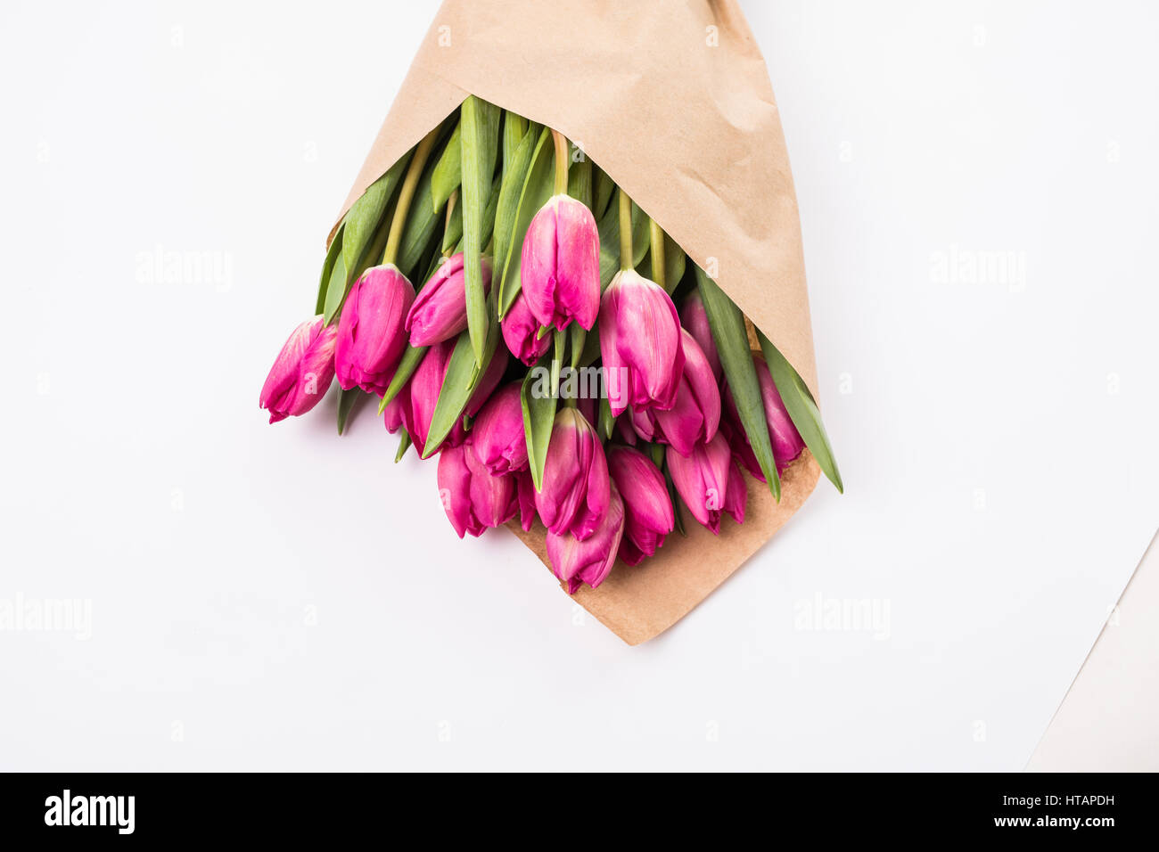 Pink tulips in a package of craft on the wooden background. Pink tulip. Tulips. Flowers. Flower background. Flowers photo concept. Holidays photo conc Stock Photo