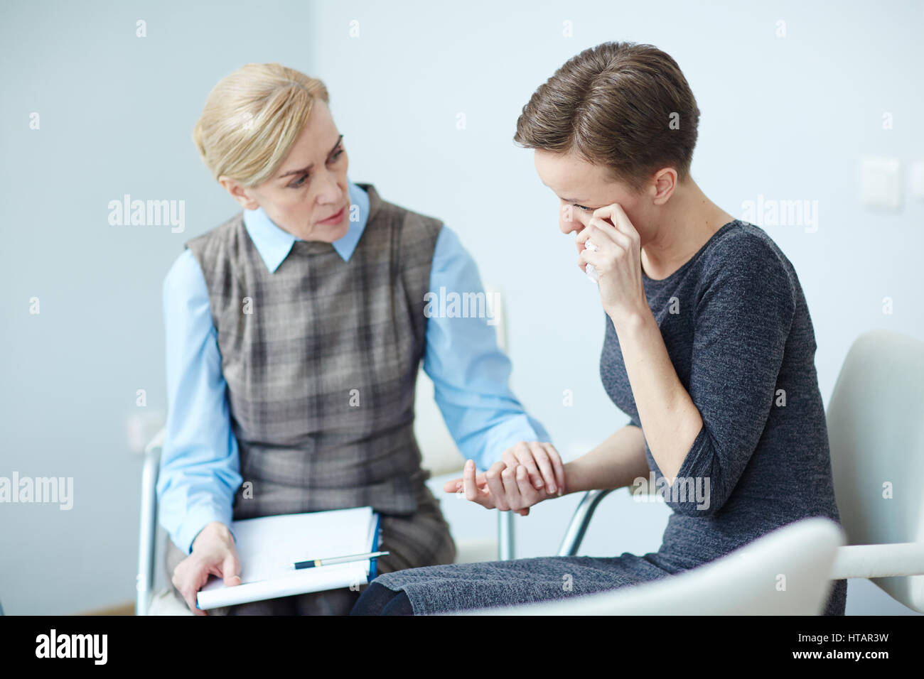 Portrait of young woman crying and opening up mental problems to mentor comforting her in psychological support meeting Stock Photo
