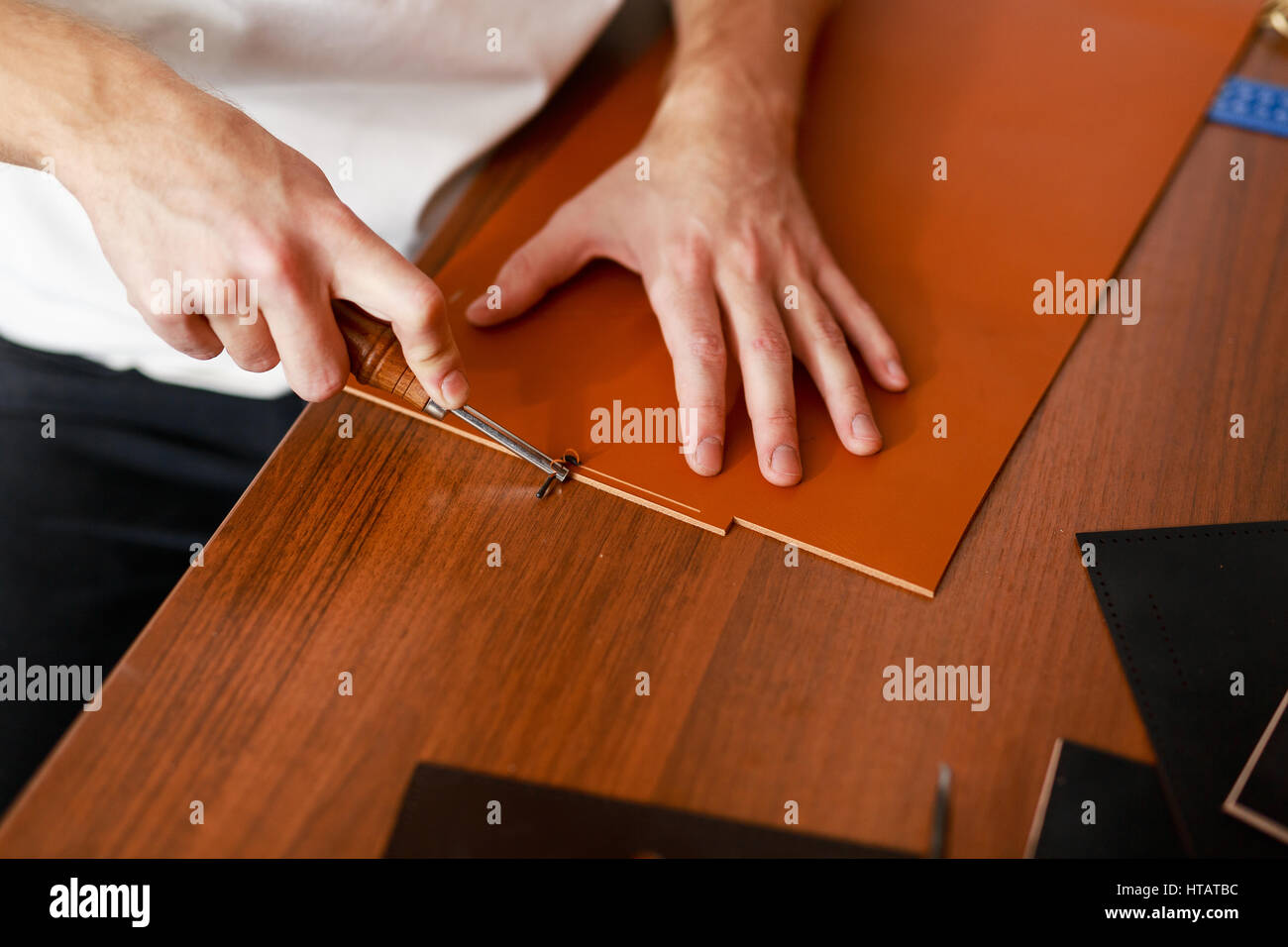 Man using special knife or cutter while processing leather workpiece ...