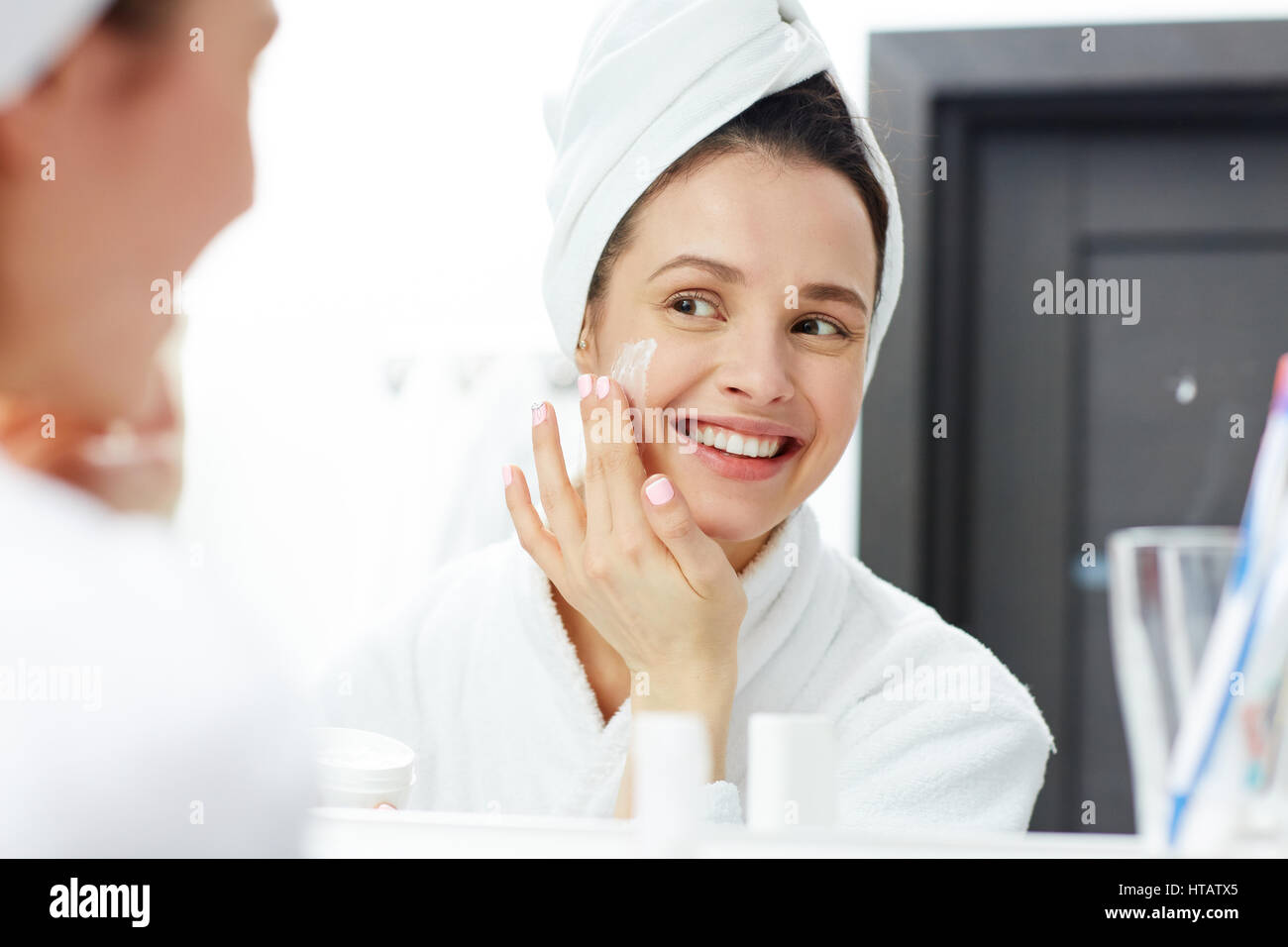 Perfect young woman applying facial cream in bathroom Stock Photo Alamy
