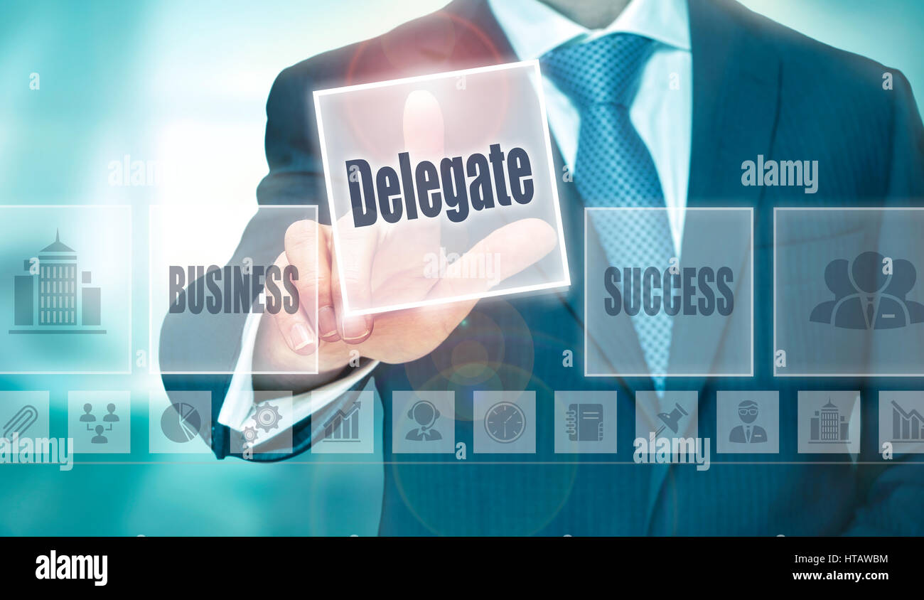 A businessman selecting a Delegate Concept button on a clear screen. Stock Photo