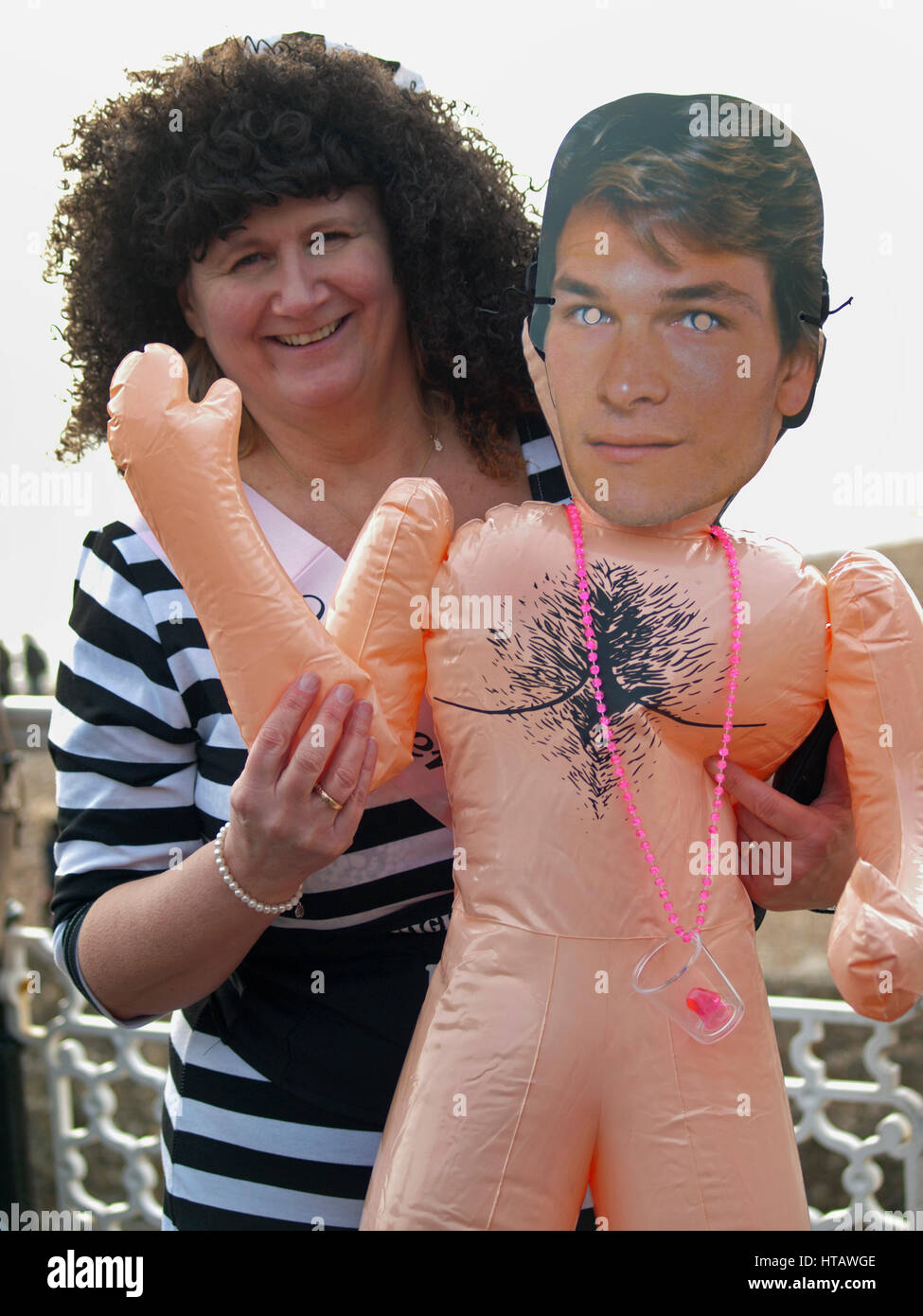 An inflatable Patrick Swayze is held by a woman on a stag do in Brighton Stock Photo