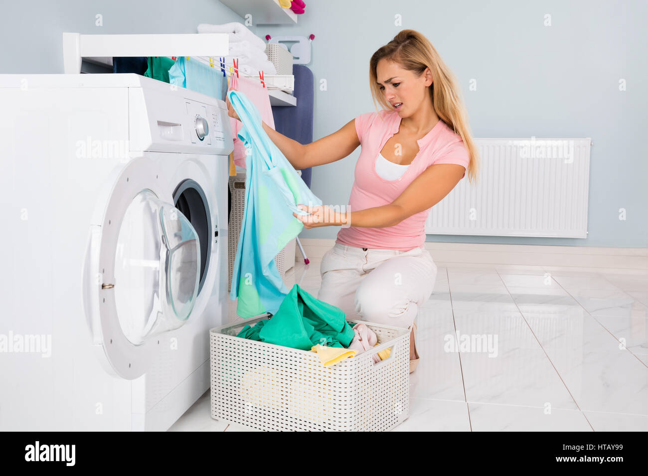Young Woman Looking At Clothes After Washing In Washing Machine At Utility Room Stock Photo Alamy