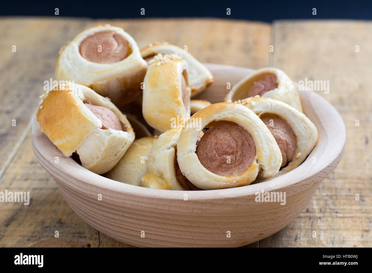 Home made pigs in a blanket. Sausages rolled in croissant dough baked cooling on metal rack with sesame. Selective focus Stock Photo