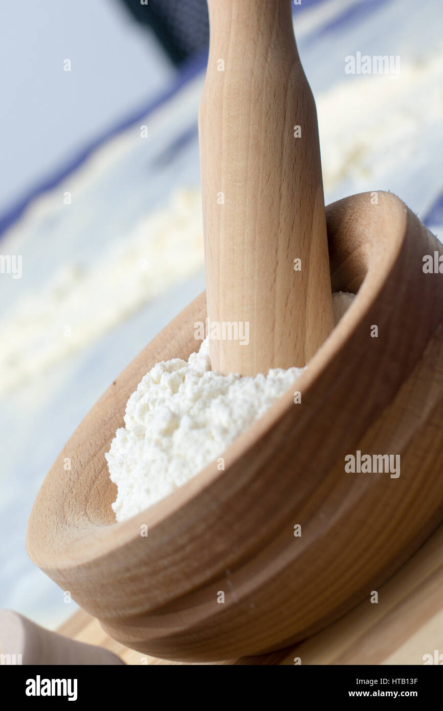 Wheat Flour in a Wooden Mortar with Pestle on a wooden plate Stock Photo