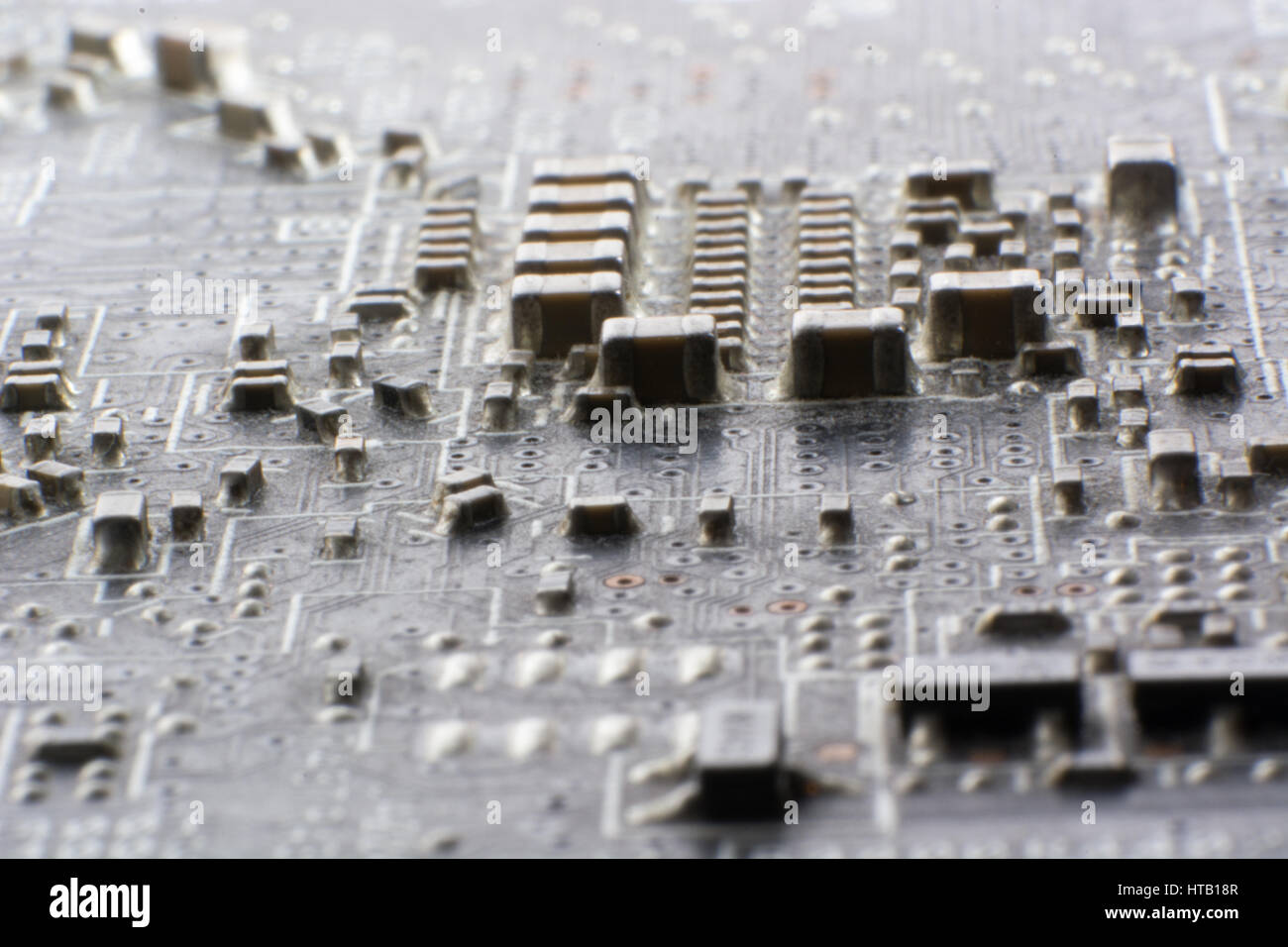 Surface-mount dusty smd components on used electronic circuit board close-up. Stock Photo