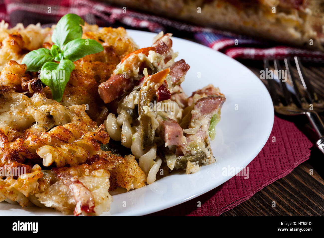 Portion of fusilli pasta casseroles, sausages and zucchini on a plate Stock Photo