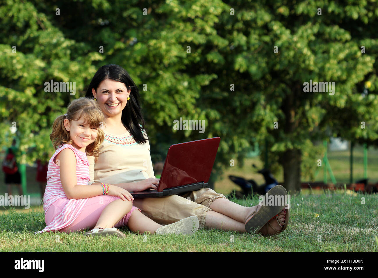 happy little girl and woman with laptop in park Stock Photo - Alamy