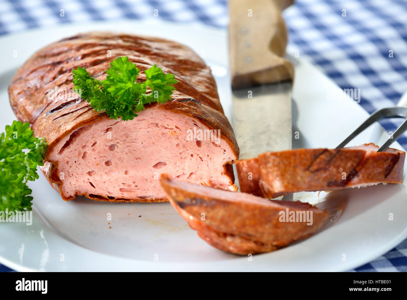 Bavarian meat loaf on a white plate served on a table with a white ...