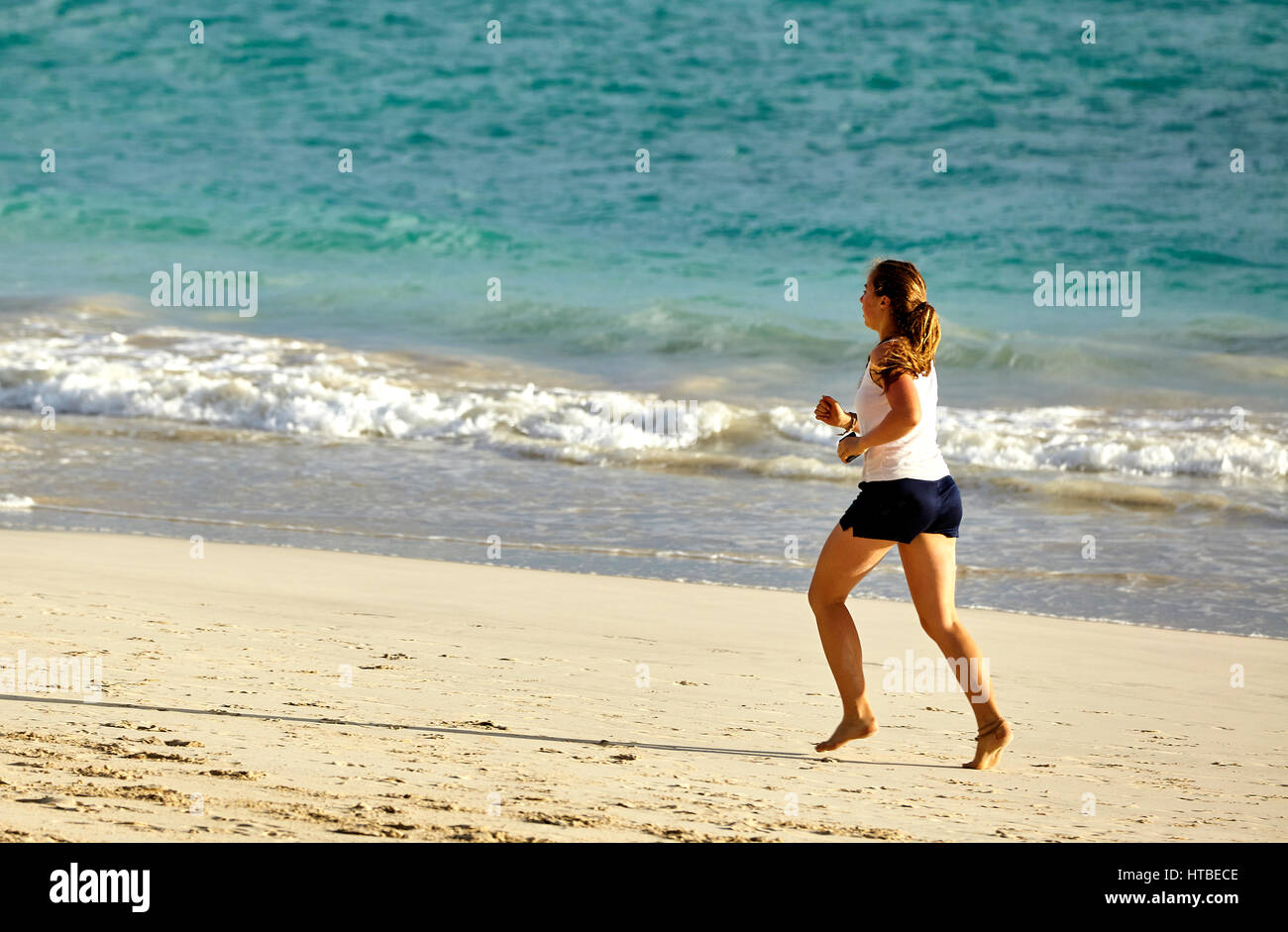 Kailua, Hawaii, USA - July 30, 2016: An unidentifed woman runs on the sandy beach along the shores of Kailua Bay in Hawaii Stock Photo