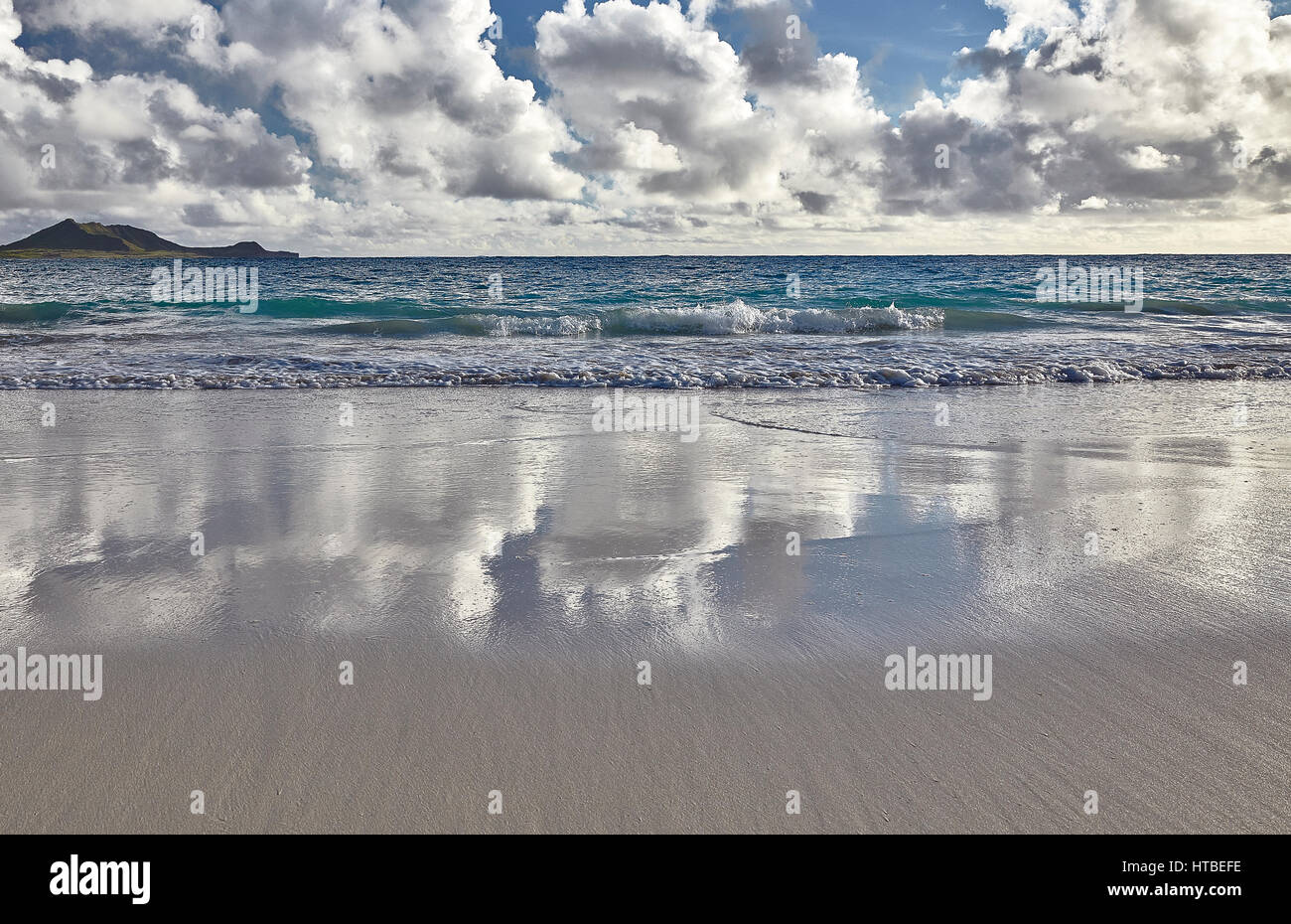 Clouds and sky reflections on tropical beach and ocean shore at sunrise Stock Photo
