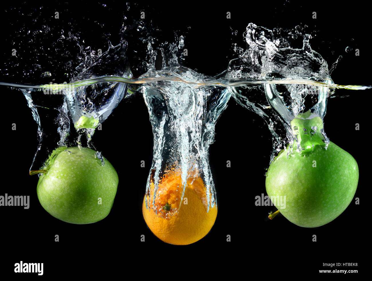 Splash water with droping oranges and apples in art mixed in studio technical speed and lighting. Stock Photo