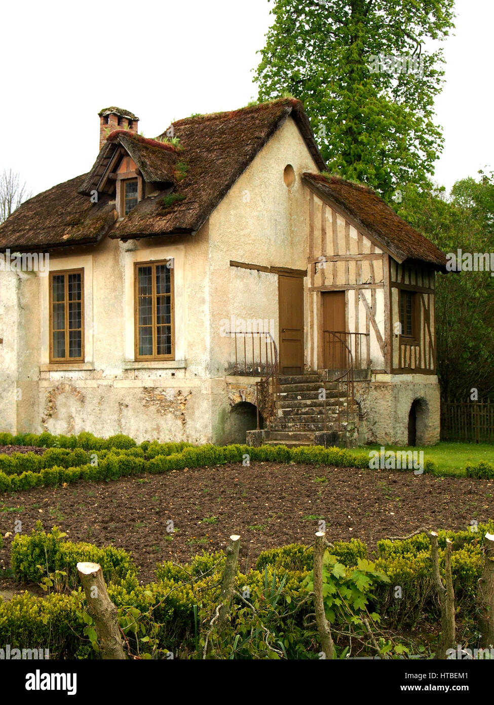 A traditional French cottage with a small garden and a thatched roof. Stock Photo