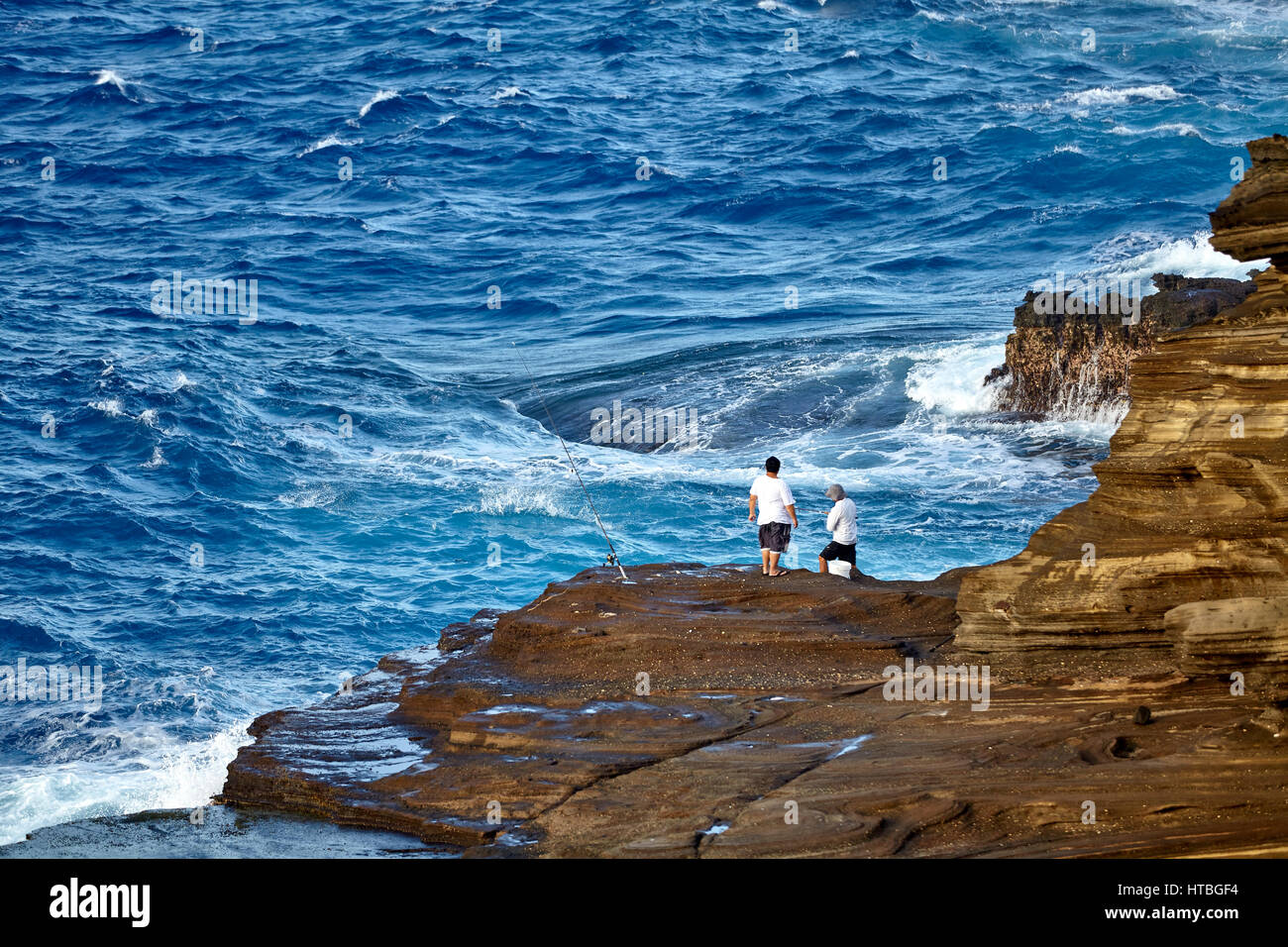 Makapuu Point, Hawaii, USA -- August 8, 2016: Unidentified fisherman at rugged Makapuu Point Hawaii USA Stock Photo