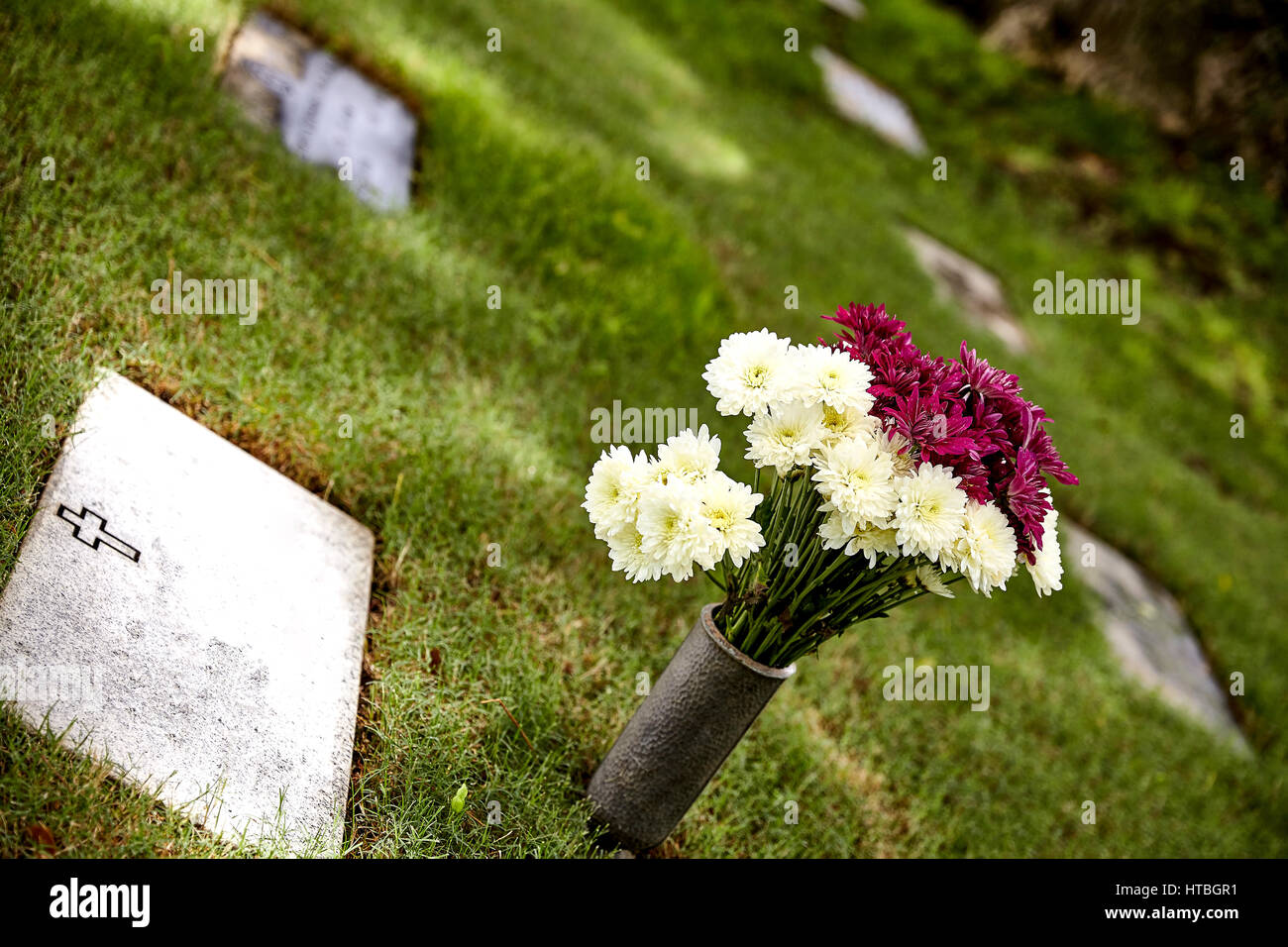 Gravestone with flowers in the shade Stock Photo