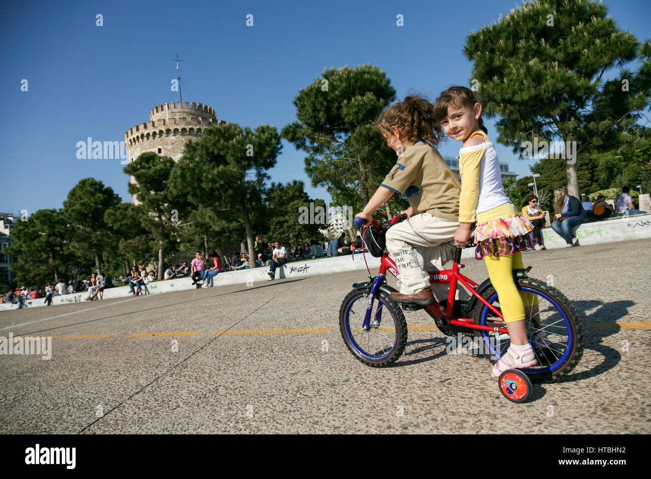 Two little girls riding one small bike 