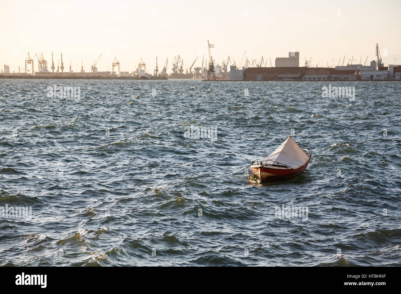 Fishing boat in a sea in Thessaloniki, Greece. Industrial sea port is visible on a horizon Stock Photo