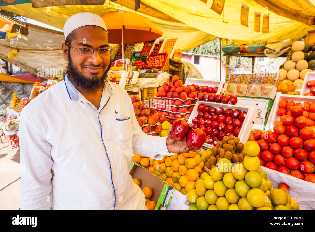 An Indian man in a fruit market in Pune, India holding up apples from