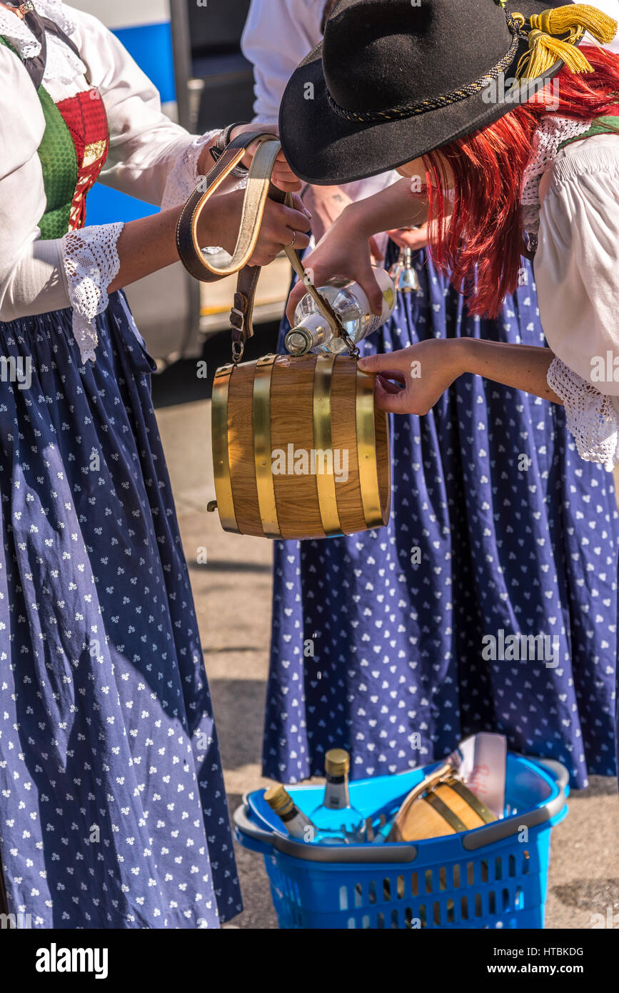 Women dressed in traditional Austrian costumes pour Schnapps into a small wooden keg. Stock Photo