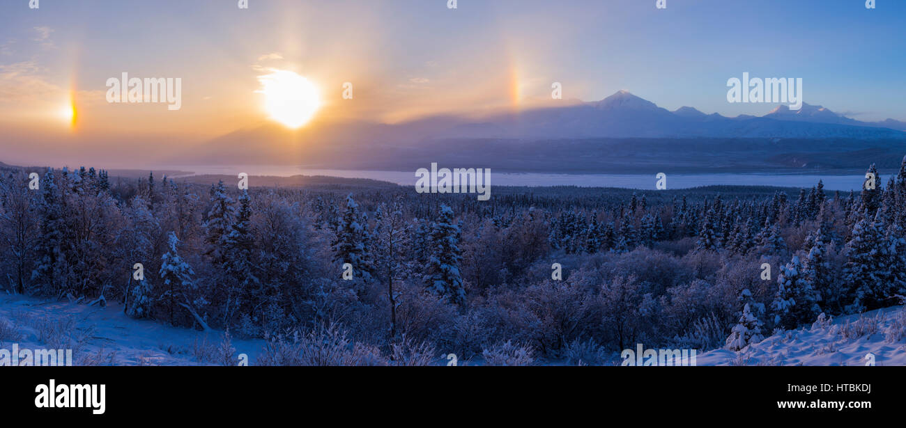 Parhelia (sundogs) surround the sun on a bitterly cold day in interior Alaska overlooking the Delta River with the Alaska Range in the background Stock Photo
