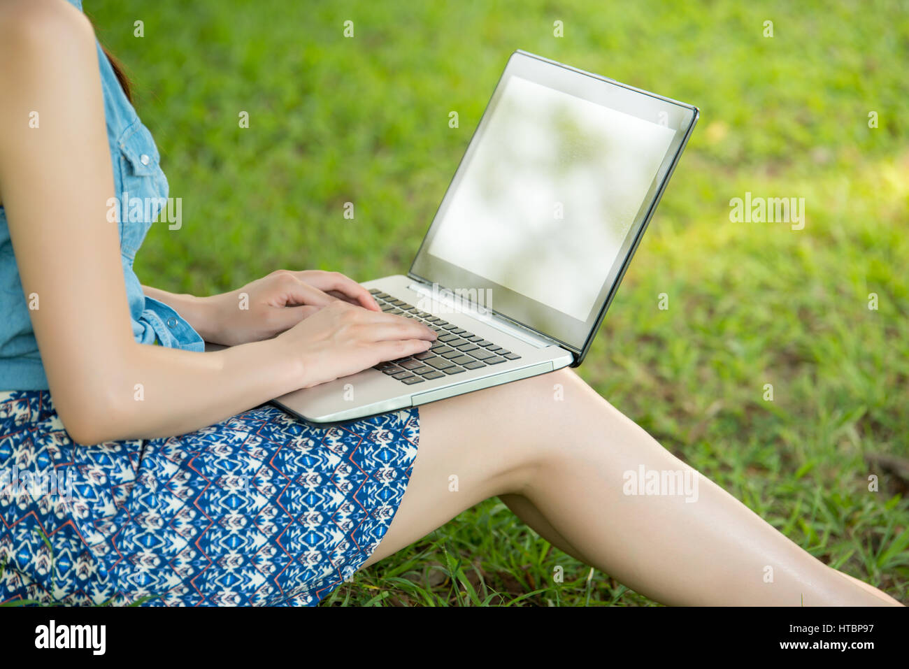 beautiful asian woman using computer sitting on grass in outdoor park ...