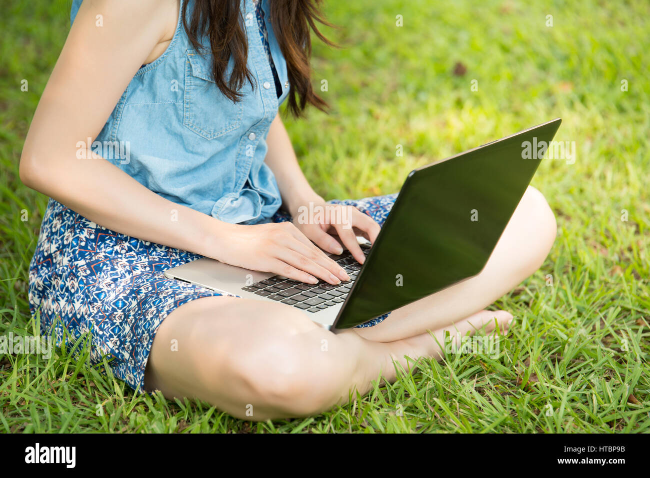 beautiful asian woman using computer sitting on grass in outdoor park ...