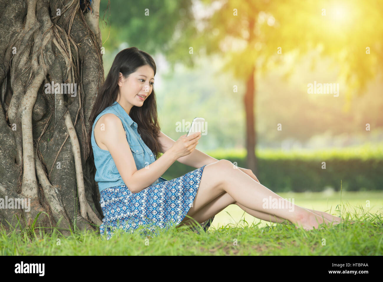 beautiful asian woman using smart phone sitting on grass in outdoor ...