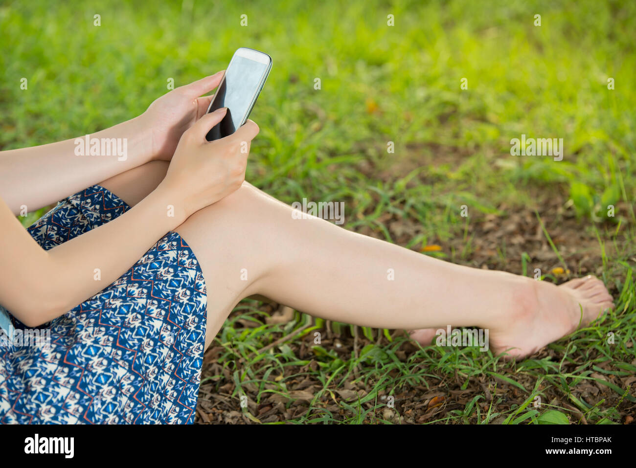 beautiful asian woman using smart phone sitting on grass in outdoor ...