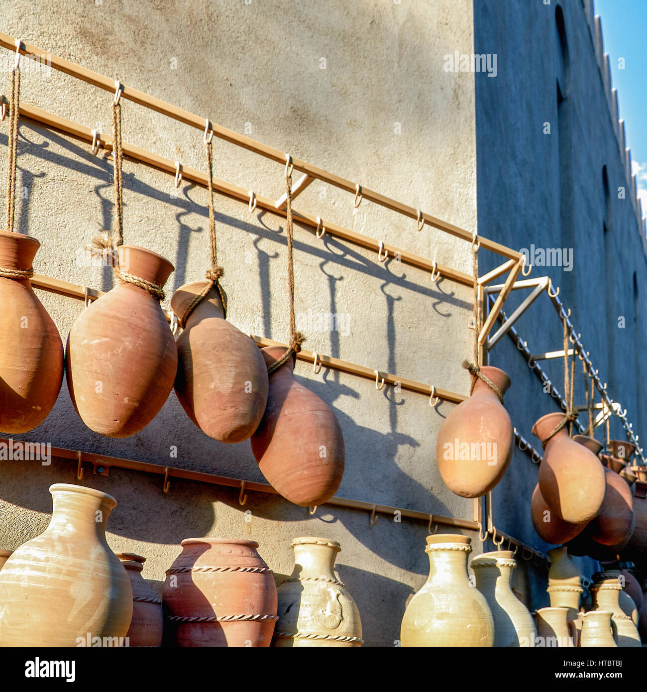 Earthenware pots hanging from ropes on display in a village market ...